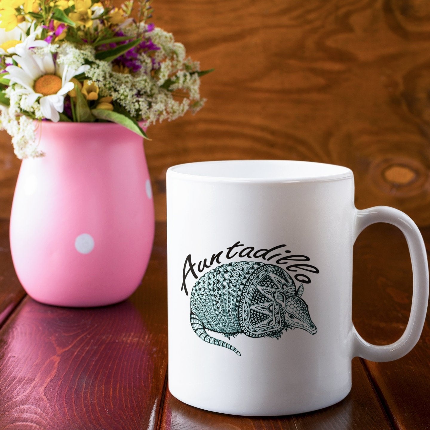 a white coffee mug sitting next to a pink vase filled with flowers