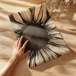 Black and beige bold sunflower botanical art print laying on a wood table