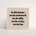 a black and beige oak framed art print with the words in this house, we do awkward, we do silly, we do crazy we do fun