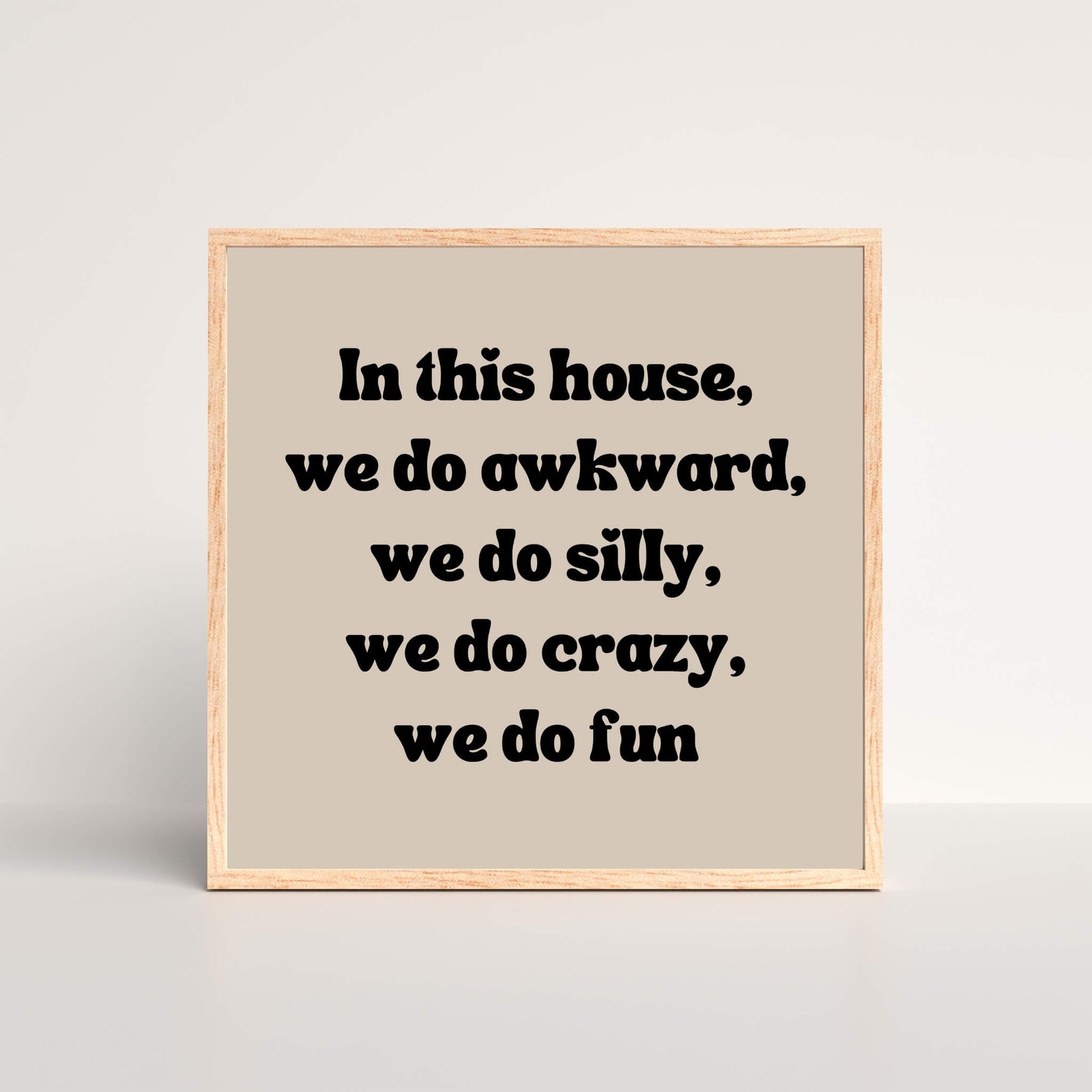 a black and beige oak framed art print with the words in this house, we do awkward, we do silly, we do crazy we do fun