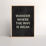 Wander Where The Wifi Is Weak Art Print with black background and white text in a oak picture frame sitting on a floor leaning against a wall