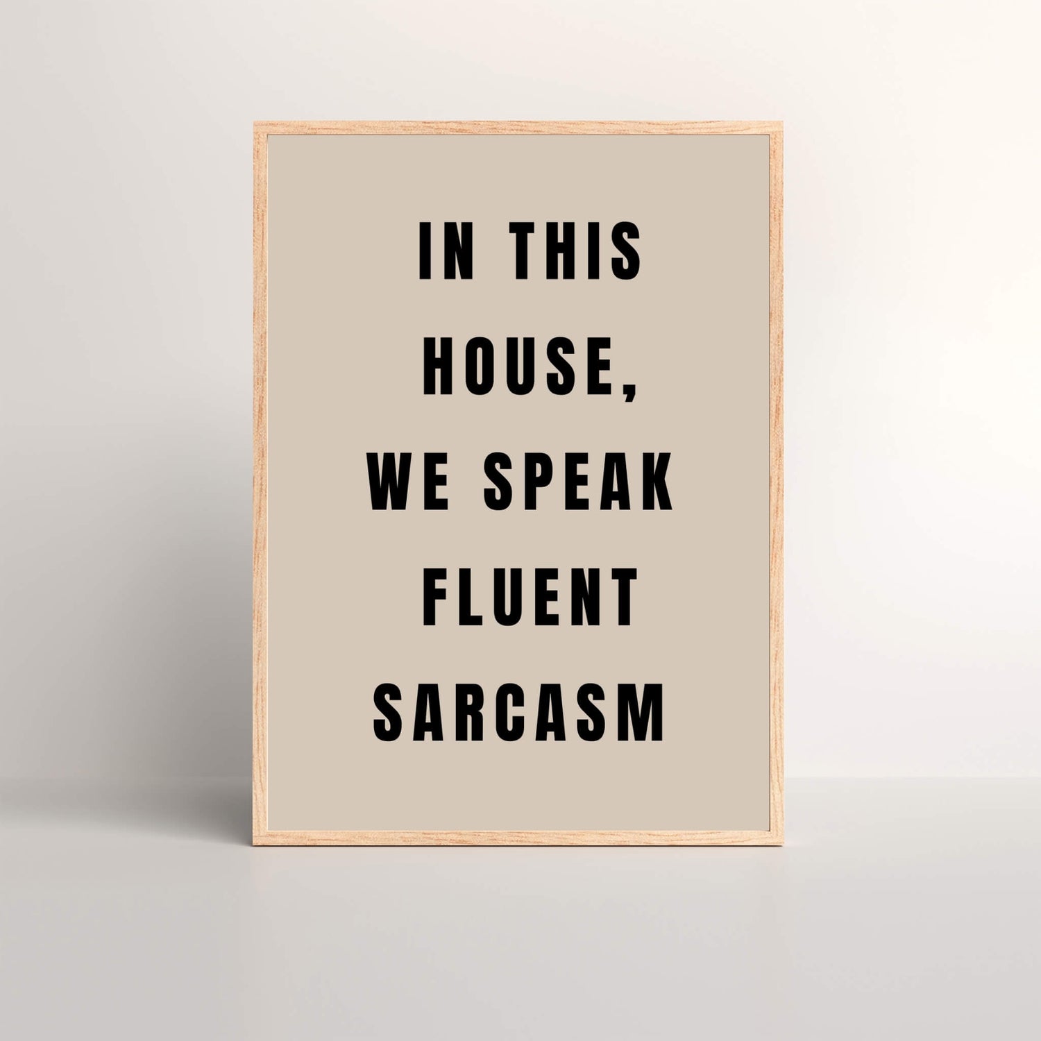 black and beige typography on an framed art print that says 'In This House, We Speak Fluent Sarcasm'