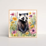 a watercolor painting of a badger in a field of colorful flowers framed art print